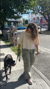 Woman wearing a beige t-shirt and green khaki pants training a dog in the Wynwood Art District in Miami.